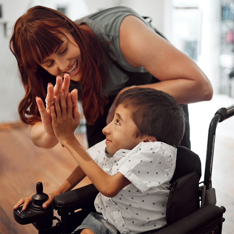 A boy in a chair being high-fived by a nurse